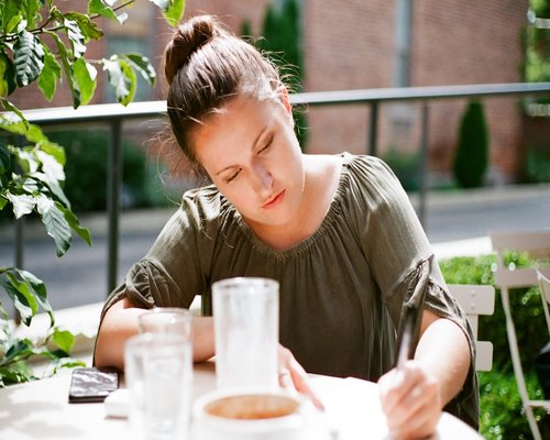Young woman studying at a sunny cafe desk