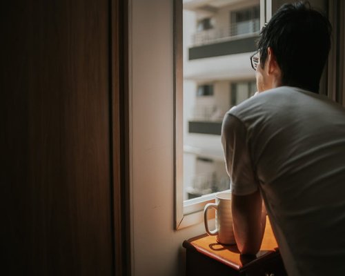 Person looking out of a window in a city apartment