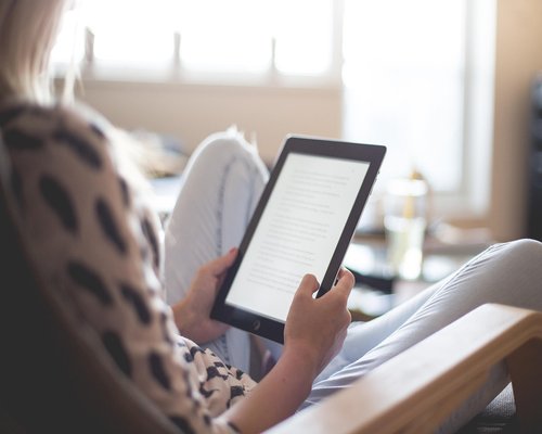 Close up of an e-reader device next to a cup of coffee